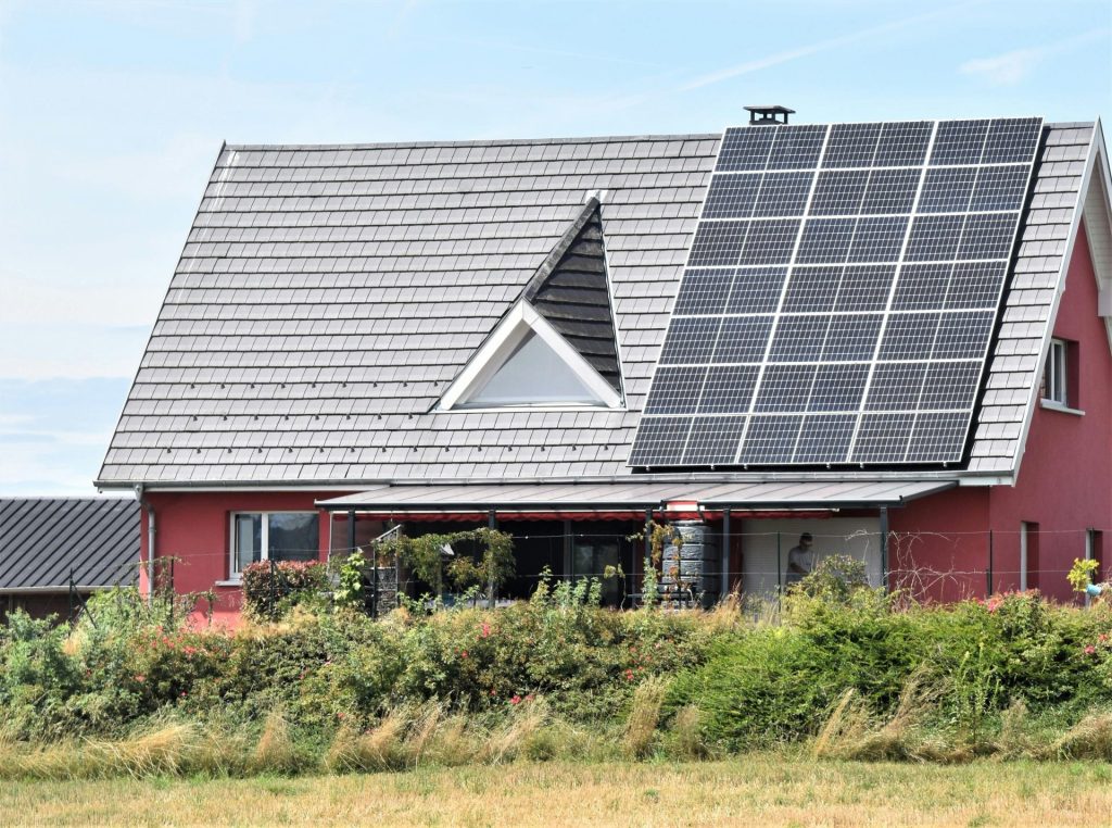 A red house with solar panels on the roof in Seppois-le-Bas, illustrating clean energy.